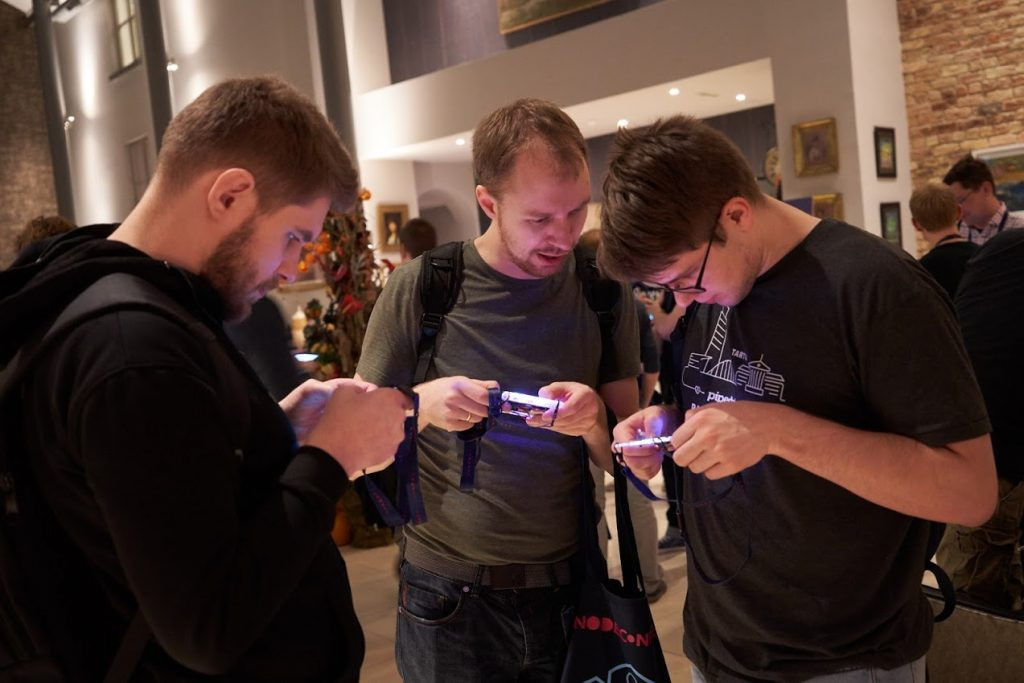 Confrence attendees examining digital badges at NodeConf EU 2018